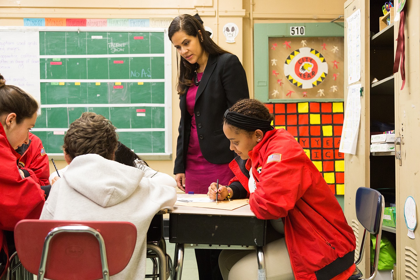 Corporate team donor observing AmeriCorps members working with students in a classroom at a table