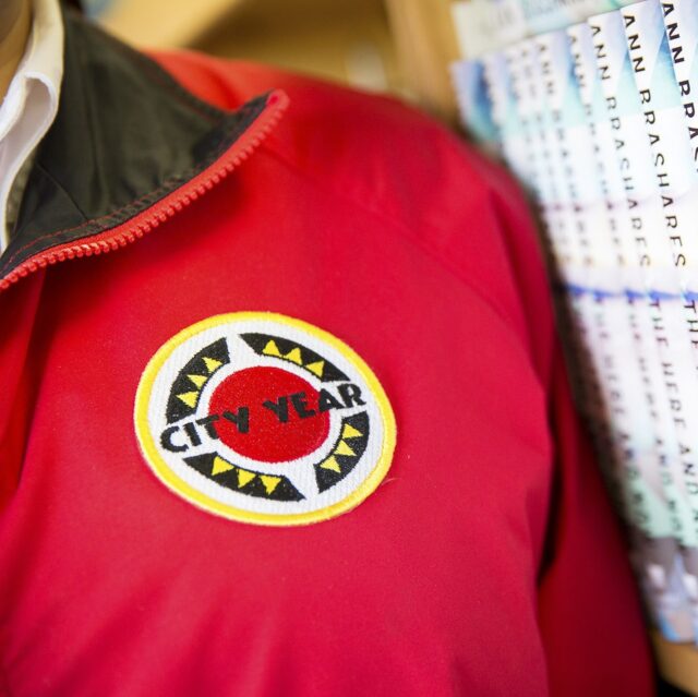 close up of AmeriCorps members' jacket, standing next to a row of books
