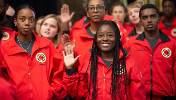 A cohort of ɫƵ AmeriCorps members raise their right hand as they say the ɫƵ pledge