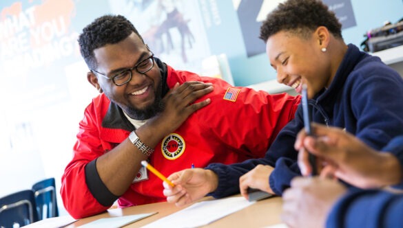 ɫƵ AmeriCorps member smiling with student in school