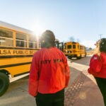 Two ɫƵ Tulsa AmeriCorps members prepare to greet students as the buses arrive