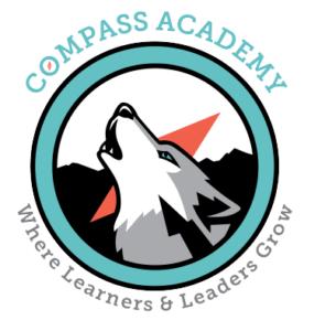Compass Academy logo, a grey howling wolf in the center of a compass with a silhouetted mountain range in the background