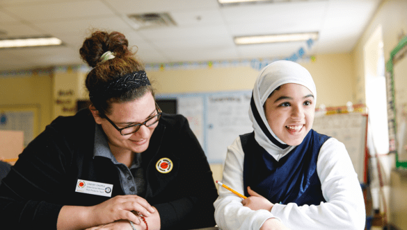 A ɫƵ Buffalo AmeriCorps member and student smile and sit at a table
